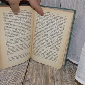 May include: An open book with green cover, showing two pages of text. The left page has the title "The Mysterious Room" and the right page has the title "Three Wise Men".