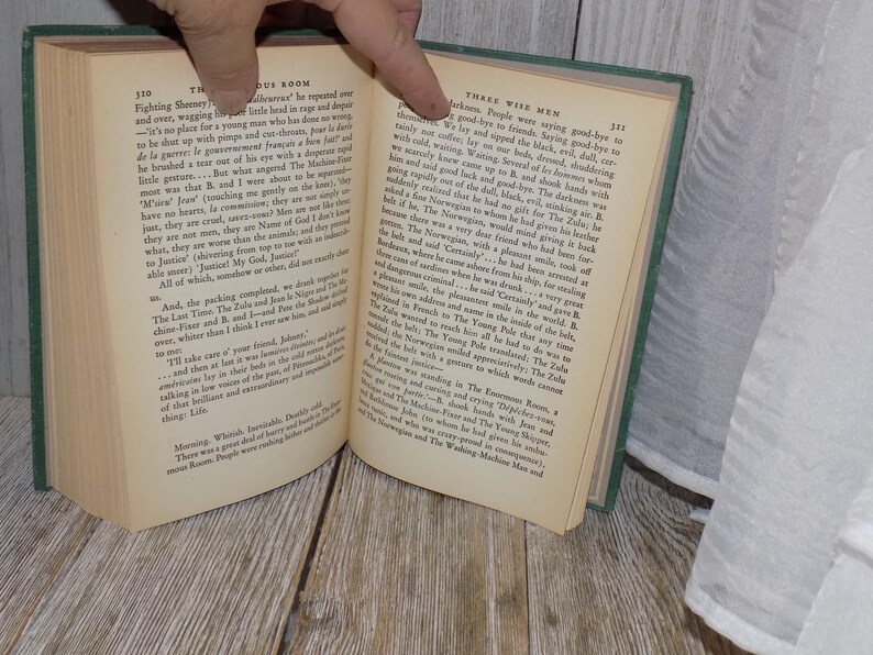 May include: An open book with green cover, showing two pages of text. The left page has the title "The Mysterious Room" and the right page has the title "Three Wise Men".
