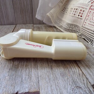 May include: A pair of off-white plastic body massagers with the words "Body Massager" printed in pink on one of the massagers.