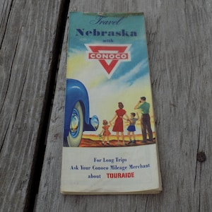 May include: Vintage travel brochure for Nebraska with Conoco branding. The cover features a blue car, a family illustration, and the text "For Long Trips Ask Your Conoco Mileage Merchant about TOURAIDE."