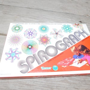 May include: Vintage Spirograph drawing toy box with colorful geometric designs and the text "SPIROGRAPH" in large letters. The box features the text "A FASCINATING WAY TO DRAW A MILLION MARVELOUS PATTERNS" and "OVER 18 MILLION SOLD". Ages 5 and up.