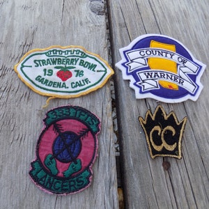 May include: Four embroidered patches. A white patch with green trim reads "Strawberry Bowl 19 76 Gardena, Calif.". A purple patch with white trim reads "County of Warner". A pink patch with green trim reads "333's Rangers". A black patch with gold trim reads "CC" with a crown above the letters.
