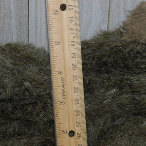 Puede incluir: Primer plano de una tela peluda marr&oacute;n y verde con una regla que mide 66 cm. La tela tiene un brillo sutil.