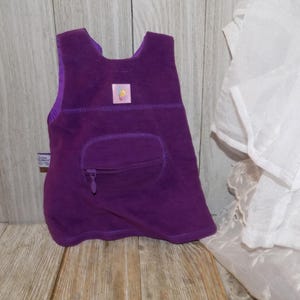 May include: Purple fleece vest with a zippered pocket and a small yellow and pink label. The vest has a sleeveless design and is made of soft, comfortable fabric.
