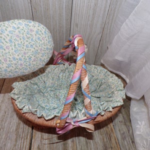 Peut inclure: Un panier en osier avec une doublure en tissu et une poign&eacute;e envelopp&eacute;e de ruban rose, bleu et blanc. Le panier est doubl&eacute; d'un tissu &agrave; imprim&eacute; floral.