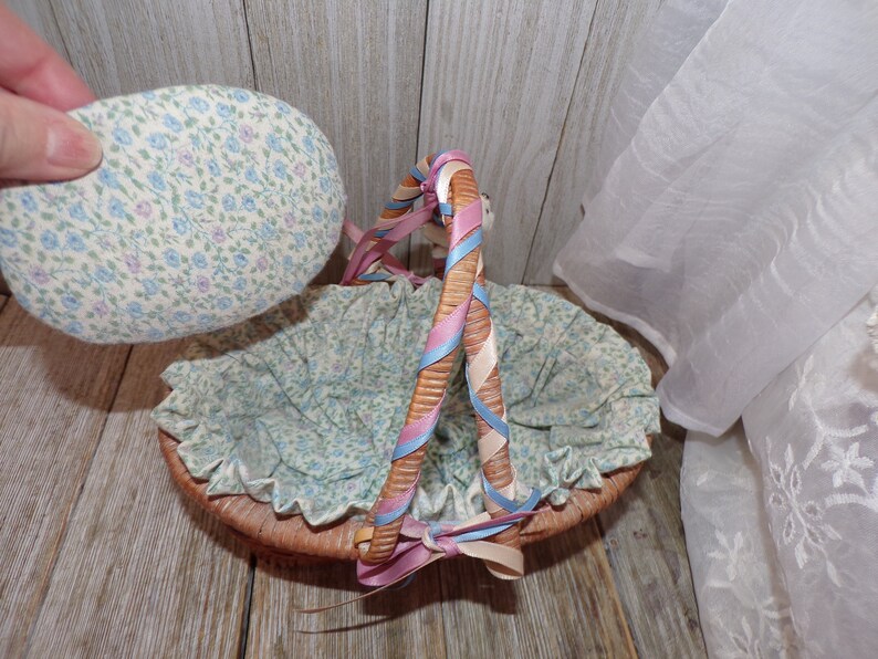 Peut inclure: Un panier en osier avec une doublure en tissu et une poign&eacute;e envelopp&eacute;e de ruban rose, bleu et blanc. Le panier est doubl&eacute; d'un tissu &agrave; imprim&eacute; floral.