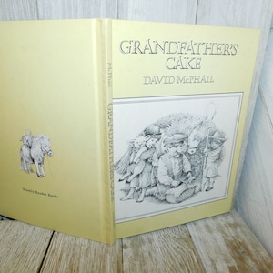 May include: A yellow book titled "Grandfather's Cake" by David McPhail. The cover features a black and white illustration of children with a sheep and a pony.