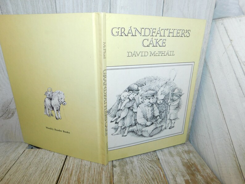 May include: A yellow book titled "Grandfather's Cake" by David McPhail. The cover features a black and white illustration of children with a sheep and a pony.