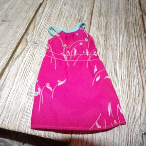 May include: A pink sleeveless dress with a floral print and a light blue trim. The dress is made of a soft, silky fabric.