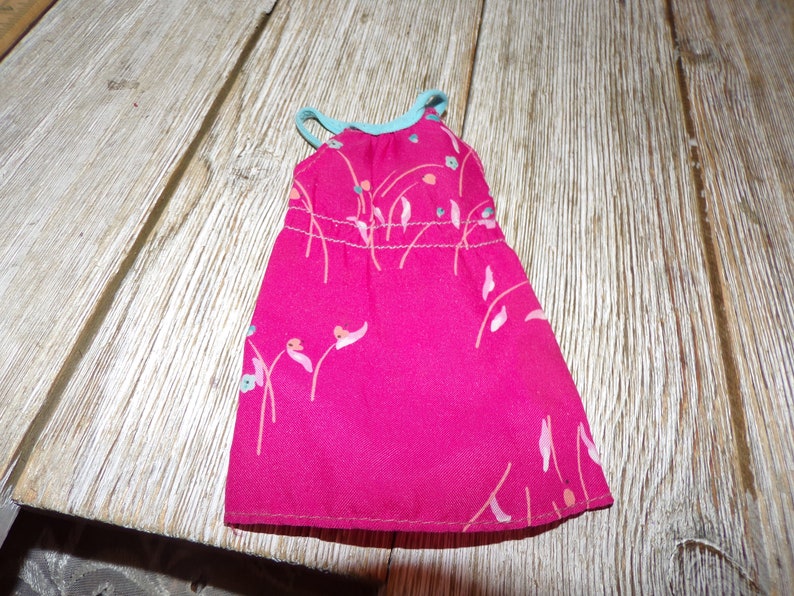 May include: A pink sleeveless dress with a floral print and a light blue trim. The dress is made of a soft, silky fabric.