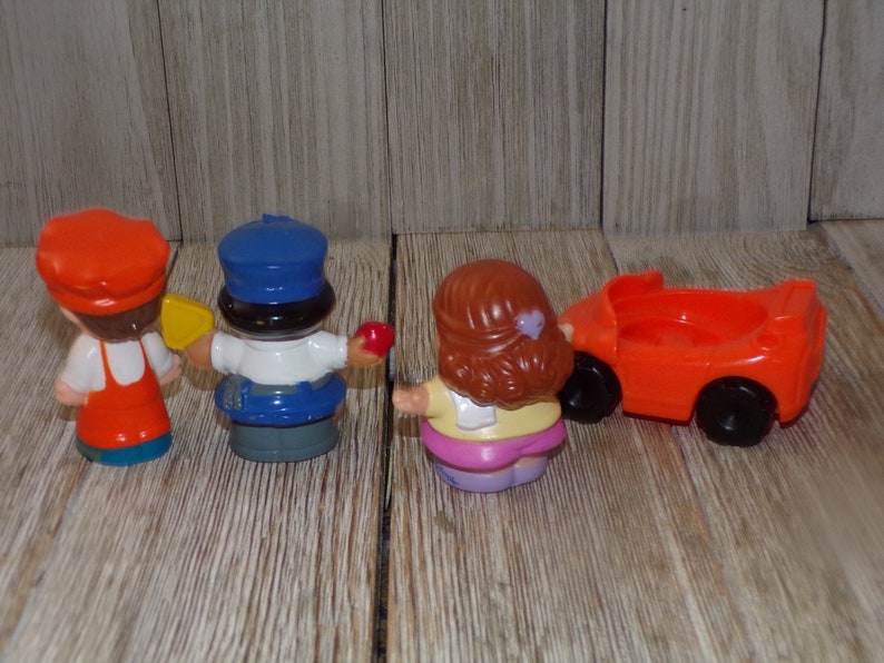 May include: A set of four plastic figurines, including a chef, a police officer, a girl, and a red toy car. The figurines are all facing away from the camera.