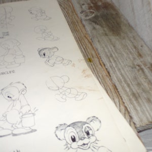 May include: A vintage drawing tutorial page featuring pencil sketches of cartoon characters. The page shows step-by-step instructions for drawing the characters, with the words "INSTRUCTION IN CIRCLES" visible. The page is set against a rustic wooden background.