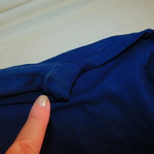 May include: Close-up of a dark blue fabric with a fold in the fabric. The fabric is smooth and has a slight sheen.