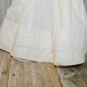 May include: A white cotton skirt with a lace trim. The skirt is gathered at the waist and has a simple, classic design.