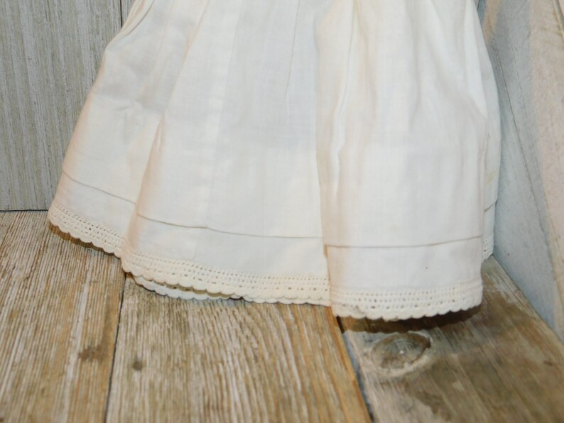 May include: A white cotton skirt with a lace trim. The skirt is gathered at the waist and has a simple, classic design.