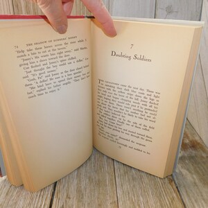 May include: A close-up of two pages from a vintage book titled "The Shadow of Robbers' Roost" and "Doubting Soldiers". The pages are yellowed with age and the text is printed in black ink.