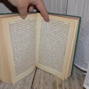 May include: An open book with green covers and white pages. The text on the pages is in black and discusses the "Enormous Room" and a "Group of Portraits".