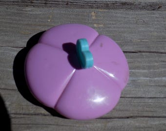 May include: A purple plastic flower with a blue butterfly-shaped button in the center.