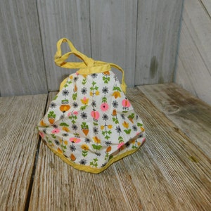 May include: A small yellow and white fabric bag with a floral print. The bag has a drawstring closure and a yellow trim.