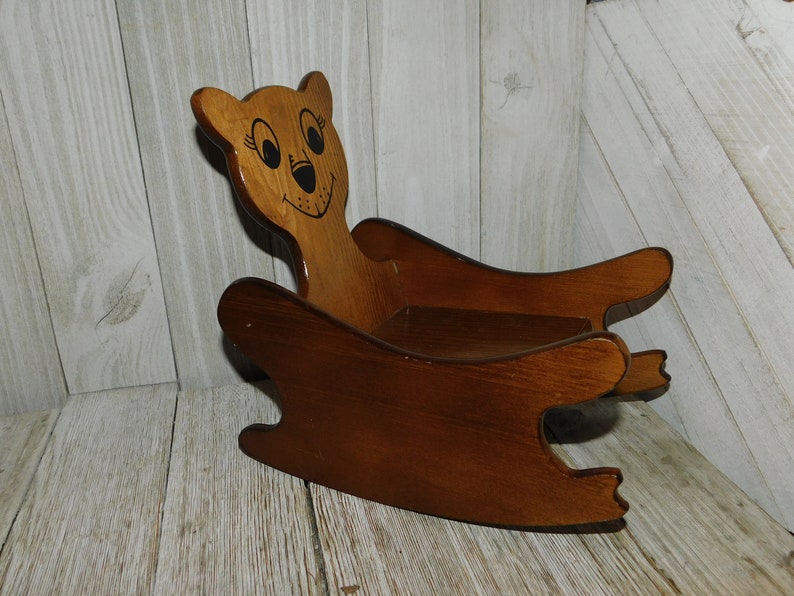 Puede incluir: Una mecedora de madera con forma de oso con la cara pintada. La silla es marr&oacute;n y tiene un dise&ntilde;o sencillo.
