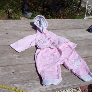 Puede incluir: Un conjunto de beb&eacute; rosa con una chaqueta con capucha y pantalones. La chaqueta tiene un dise&ntilde;o floral y los pantalones tienen un dise&ntilde;o de mariposa.