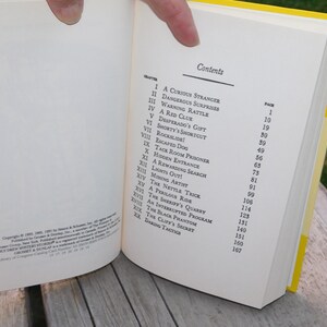 May include: A book titled "The Black Phantom" with a yellow spine and a white cover. The table of contents lists the chapters and page numbers for the book.