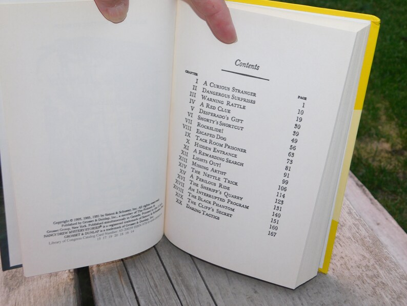 May include: A book titled "The Black Phantom" with a yellow spine and a white cover. The table of contents lists the chapters and page numbers for the book.