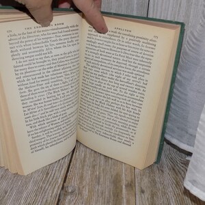 May include: Open book with green cover, showing pages with text about the Eno Room and Spollyon. The text is in black font.