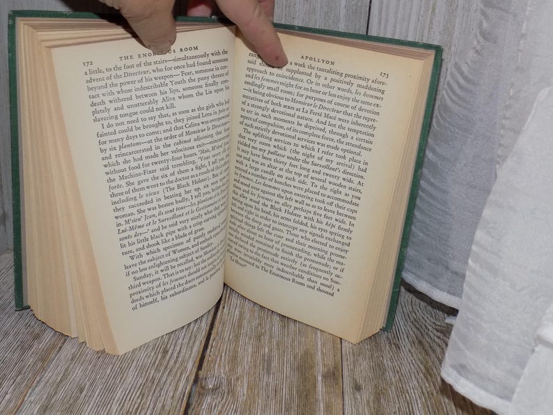May include: Open book with green cover, showing pages with text about the Eno Room and Spollyon. The text is in black font.