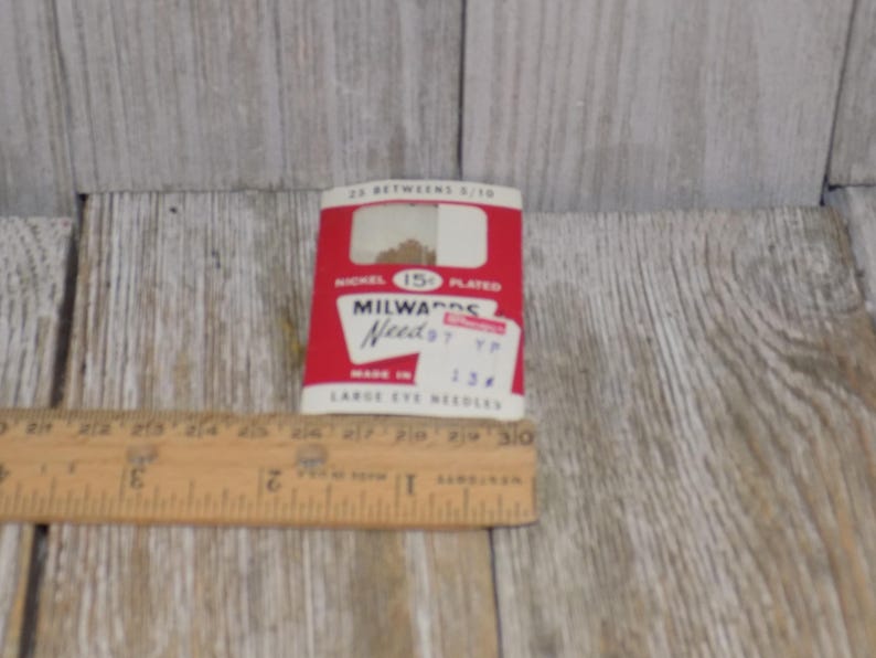 Pode incluir: Um pequeno pacote de cart&atilde;o vermelho e branco de agulhas Milwards, tamanho 7, 13/4 polegadas de comprimento, niqueladas, com uma etiqueta de pre&ccedil;o de 15 centavos.