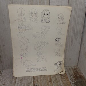 May include: A vintage sheet of paper with pencil sketches of a cartoon dog in various poses. The drawings show construction and action diagrams to help with animation. The paper is aged with visible wear and tear.