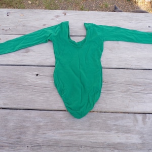 Puede incluir: Un leotardo de manga larga de color verde brillante con cuello redondo.