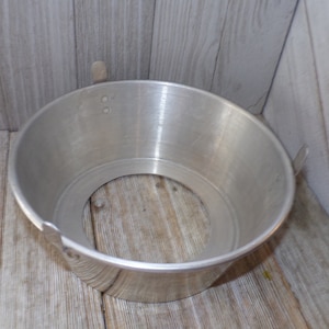 May include: A silver metal cake pan with a removable bottom and a ring around the top. The pan is designed for making bundt cakes.