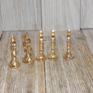 May include: Set of six gold-tone metal decorative place card holders. Each holder features a decorative design with a raised centre.