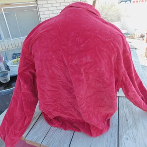 May include: A red velvet jacket with long sleeves and a button-up collar.
