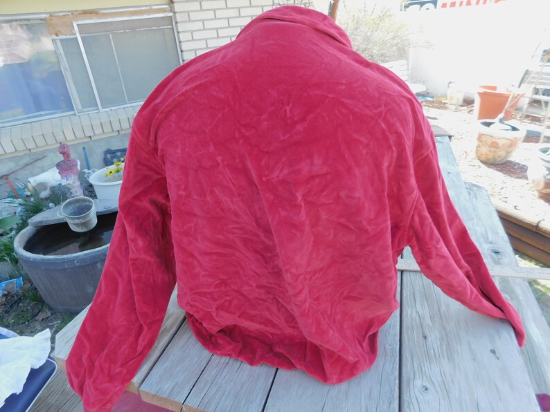 May include: A red velvet jacket with long sleeves and a button-up collar.