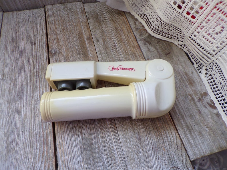 May include: A white handheld body massager with three rolling balls and a red "Body Massager" label.