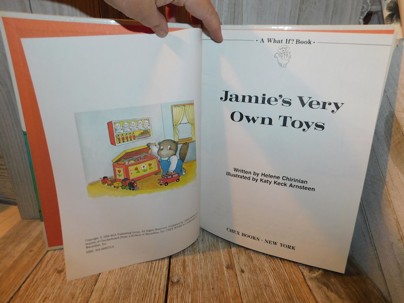May include: A children's book titled "Jamie's Very Own Toys" by Helene Chirinian, illustrated by Katy Keck Arnsteen. The cover features a cartoon illustration of a bear opening a toy chest.