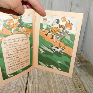 Op de afbeelding: Een open boek met kleurrijke illustraties van kinderen die buiten spelen. De tekst op de pagina luidt: "Girls and boys come out to play The sun shines bright this lovely day Finish your breakfast of good things to eat... And join your playmates down on the street Come with a hoop and come with a ball. Come with a kite and come with a doll. Come with laughter merry and gay To play out of doors this livelong day"