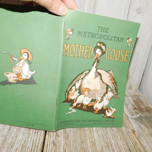Op de afbeelding: Een vintage groen boek getiteld "The Metropolitan Mother Goose" met een illustratie van een moedergans en haar gansjes op de omslag. De Metropolitan Life Insurance Company staat afgedrukt onderaan de omslag.