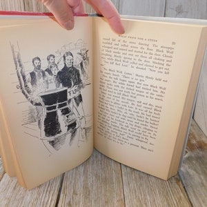 May include: A black and white illustration of a group of people standing around a large metal stove with a sign that reads "Flour". The illustration is from a book titled "What Price for a Steer".