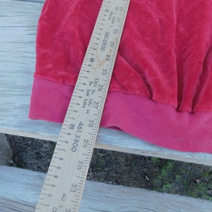 May include: A close-up of the bottom edge of a red velvet garment. A wooden ruler is visible with markings in inches and centimeters. The ruler reads "461-3800" and "2301 So. 300 W. So. Salt Lake".