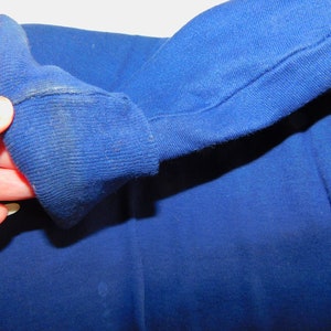 May include: Close-up of the blue fabric cuff of a long-sleeved shirt. The fabric is soft and has a slight texture.