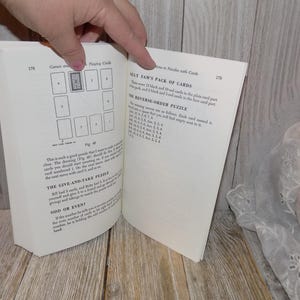 May include: A book open to a page with instructions for playing card games. The page includes a diagram of a card game and a list of instructions for a game called "Silly Sam's Pack of Cards".
