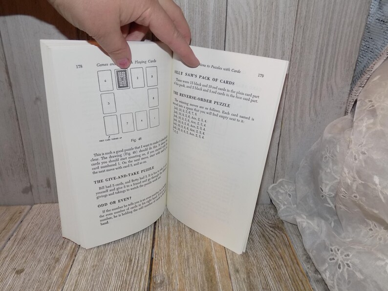 May include: A book open to a page with instructions for playing card games. The page includes a diagram of a card game and a list of instructions for a game called "Silly Sam's Pack of Cards".