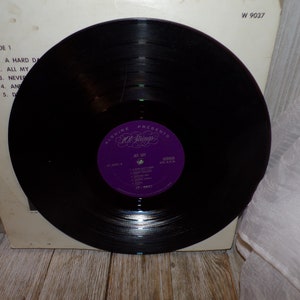 Puede incluir: Un disco de vinilo negro con una etiqueta morada que dice "Alshire Presents All Strings" y "Jet Set" con una lista de canciones. El n&uacute;mero del disco es W 9037.