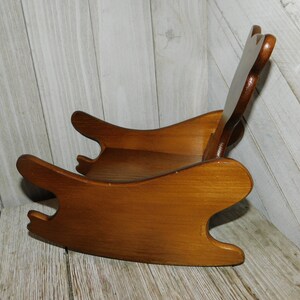 Puede incluir: Una silla mecedora de madera para ni&ntilde;os, con un acabado de tinte marr&oacute;n. La silla tiene un dise&ntilde;o sencillo con un respaldo redondeado y un asiento ancho.