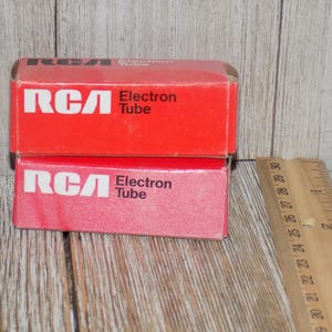 May include: Two red RCA Electron Tube boxes stacked on top of each other. The boxes have white text and logos. A wooden ruler is next to the boxes, showing inch measurements.