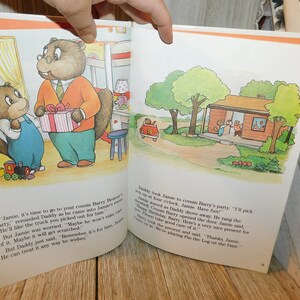 May include: A brown and white illustrated book with a picture of a beaver family. The text on the page reads, "Jamie, it's time to go to your cousin Barry Beaver's party."  The book is open to a page with a picture of a beaver giving a toy truck to another beaver.