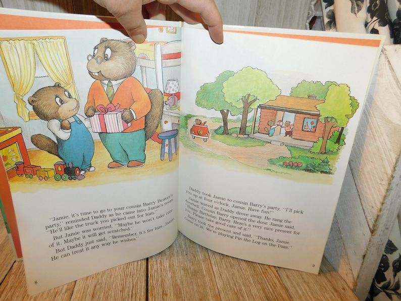 May include: A brown and white illustrated book with a picture of a beaver family. The text on the page reads, "Jamie, it's time to go to your cousin Barry Beaver's party."  The book is open to a page with a picture of a beaver giving a toy truck to another beaver.